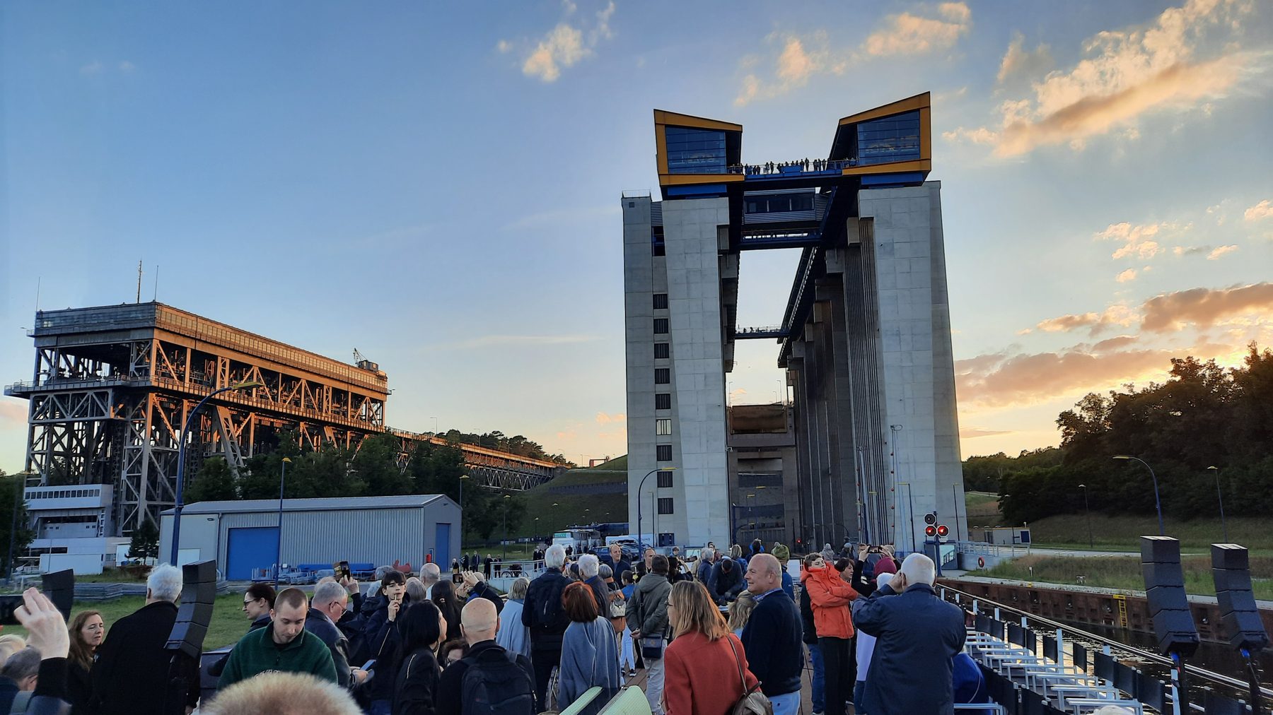 Zuhörer am Abend vor dem Hebewerk, dahinter das alte Schiffshebewerk und der Turm im Abendlicht