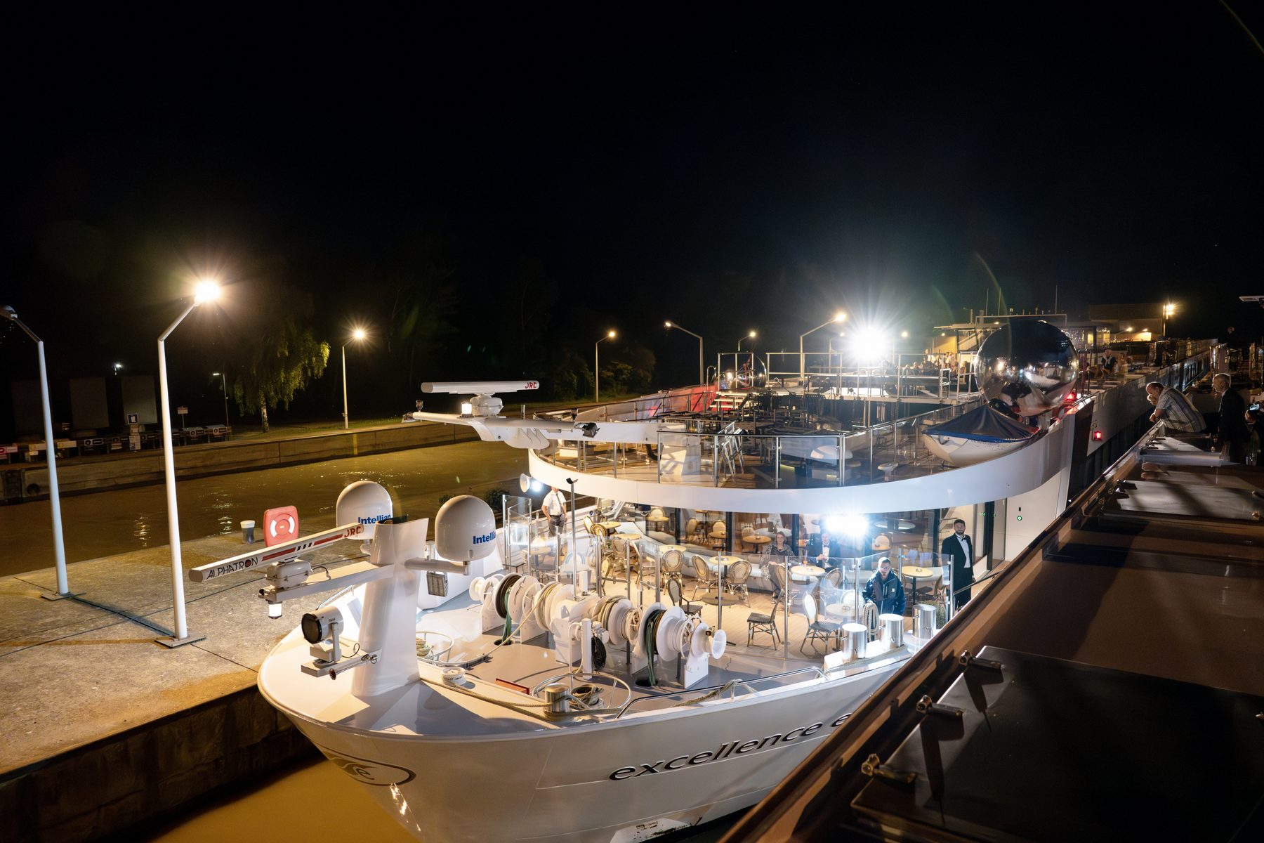 Das beleuchtete Flussschiff Excellence nachts in der Schleusenkammer, an Bord die Bühne