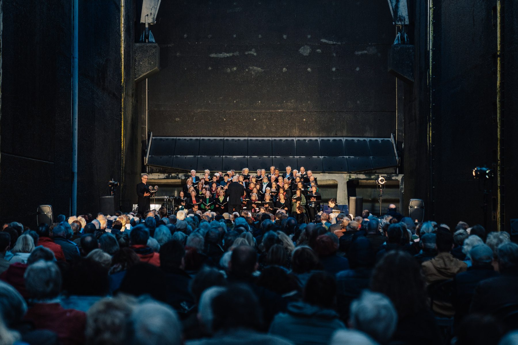 Ein Chor singt hinten in der Schleusenkammer, davor dicht besetzte Reihen von Zuhörern