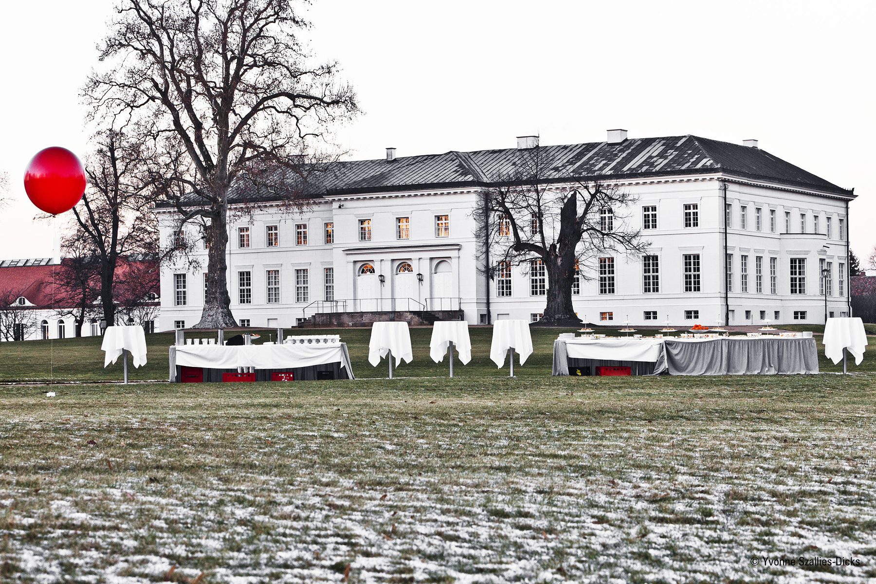 Schloss Neuhardenberg im Winterlicht, links ein roter Luftballon, davor Tische auf dem Rasen
