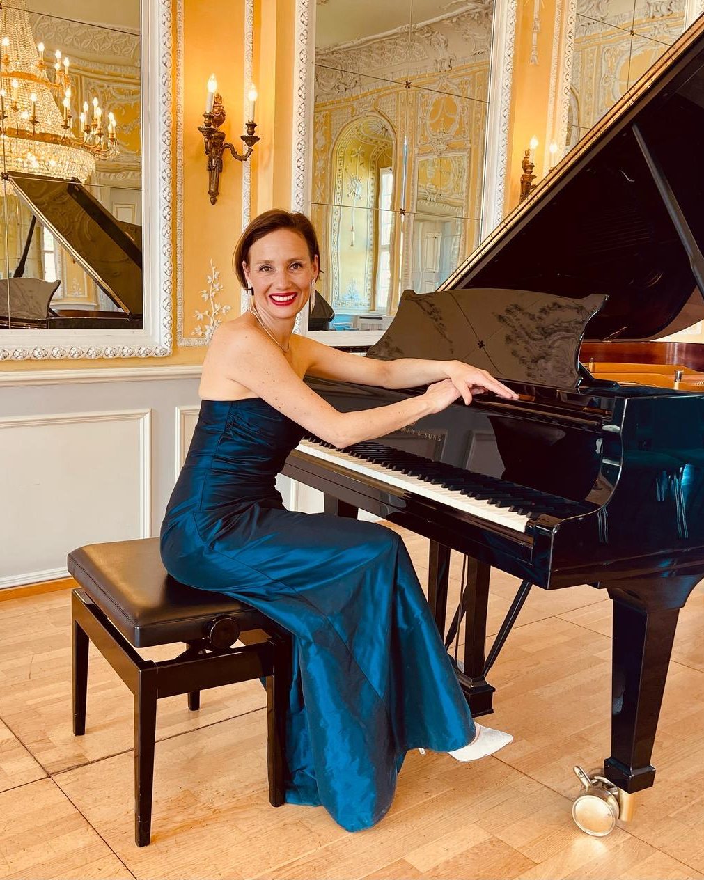 Katharina Landl im blauen Abendkleid am Steinway-Flügel in einem Spiegelsaal